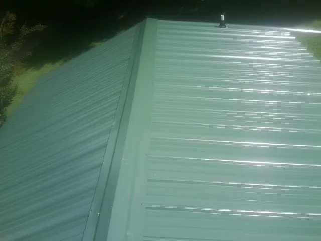 New green metal panels meeting at the ridge of a roof — Flat Roof Repair work by our crew in Confluence