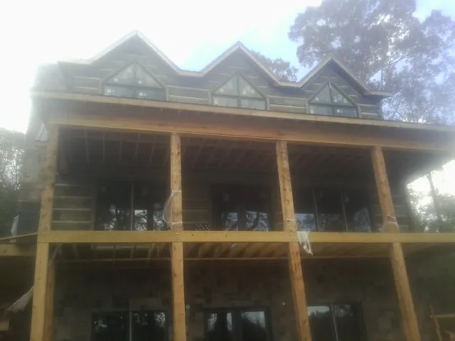 Dormers and porch framing on a large log home under construction — Roof Coating work by our crew in Confluence