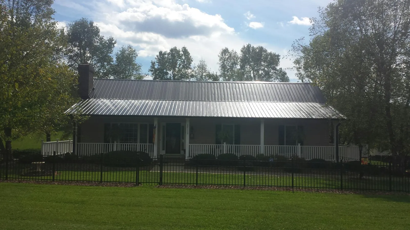 Gray metal roof on a brick ranch with a full width front porch — Gutter Guard Installation work by our crew in Confluence