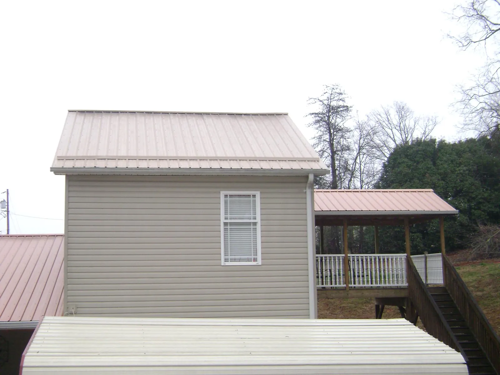 Tan metal roofs on a two story addition and attached porch, from a Roof Replacement job in Confluence