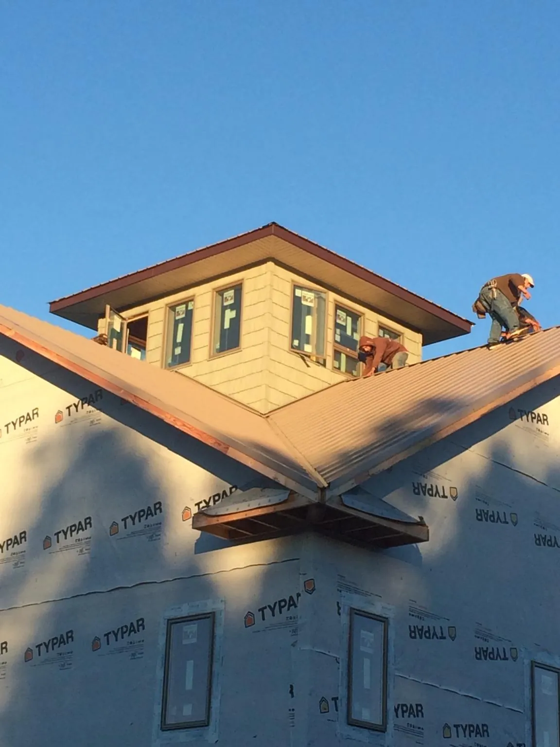 Roofers working around a rooftop cupola on a new metal roof at sunset — Roof Waterproofing in Confluence by Roofing Brothers